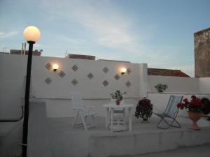 un patio con sillas, una mesa y una pared blanca en La Dimora dell'800, en Trapani