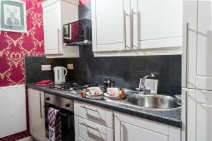 a kitchen with white cabinets and a sink at The Bonnie Bide Awa' in Edinburgh