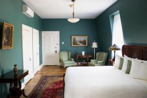 a bedroom with blue walls and a bed and chairs at Queen Anne Inn in Annapolis Royal