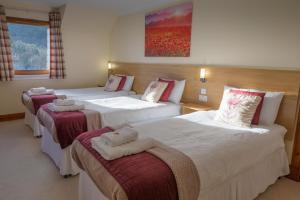 a hotel room with three beds with towels on them at Bracarina House Bed & Breakfast & Caledonian Studio in Invermoriston