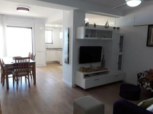 sala de estar con mesa de comedor y TV en Apartamento 1 línea playa Porsa playa Alboraya, en Port Saplaya