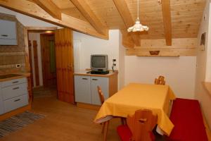 a kitchen with a table and a tv in a room at Tobià de Barat in Pozza di Fassa