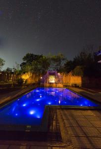 una piscina azul por la noche con una casa en el fondo en Forestville Yala en Yala