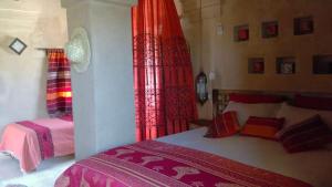 a bedroom with two beds and red curtains at Dar Lorkam in Skoura +97 photos