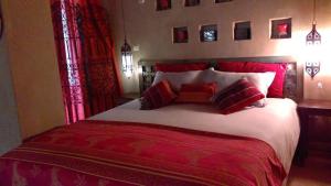 1 dormitorio con 1 cama grande con sábanas y almohadas rojas en Dar Lorkam, en Skoura