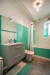 a green bathroom with a sink and a toilet at Appart PP in Douarnenez