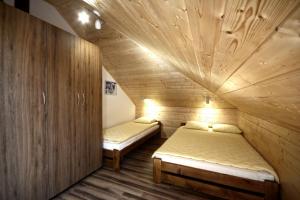 two beds in a small room with wooden walls at Duet in Karwia