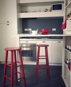 een keuken met twee rode krukken en een fornuis bij Appartamento Romantico in Cremona