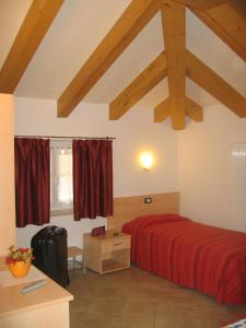 una camera con letto rosso in una stanza con soffitti in legno di Hotel Victory a Taio
