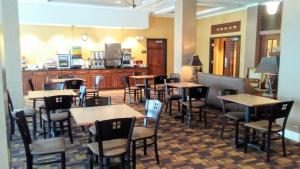 a restaurant with tables and chairs and a kitchen at Astoria Hotel & Suites - Glendive in Glendive