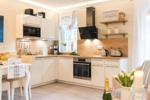 cocina con armarios blancos y mesa en Villa Strandblick 9 en Zingst