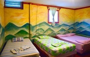 Duas camas num quarto com um mural de montanha em Hospedaje Central em Moyogalpa