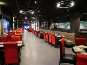 a dining room with red chairs and tables at Hotel het Oosten in Alphen aan den Rijn