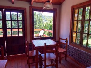 a dining room with a table and chairs and windows at Albergue Gaia in El Bolsón