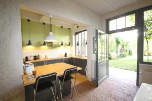 eine Küche mit einem Holztisch und Stühlen in der Unterkunft La maison du fond du jardin in Brüssel