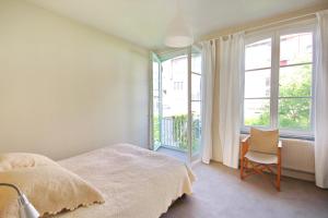a bedroom with a bed and a chair and windows at La maison du fond du jardin in Brussels