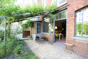 eine Terrasse mit Stühlen und einem Tisch vor einem Backsteingebäude in der Unterkunft La maison du fond du jardin in Brüssel
