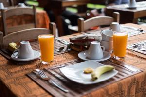 una mesa con un plato de comida y dos vasos de zumo de naranja en Wasai Puerto Maldonado Hostel, en Puerto Maldonado