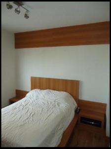 1 dormitorio con cama blanca y cabecero de madera en Curta Florianópolis em Alto Padrão, en Florianópolis