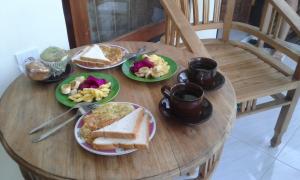 a wooden table with plates of food on it at Madu Sentana House in Ubud
