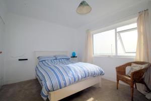 a bedroom with a bed and a window and a chair at Pebbles Beach House By Air Premier in Seaford