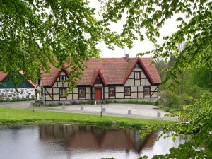 Gärsnäs的住宿－Stockeboda Gård，湖边一座红屋顶建筑
