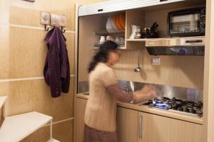 Una donna in piedi in una cucina che prepara il cibo di Trio D'Archi - Il Cortiletto a Caltagirone