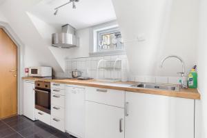 una cocina con armarios blancos y fregadero en SG Apartments, en Bergen