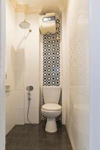 uma casa de banho branca com um WC e um chuveiro em Puri Agung Homestay em Kuta