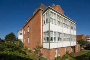 un edificio in mattoni rossi con un bianco di Haus Therese Ferienwohnung *Feodora* (App.11) a Wittdün