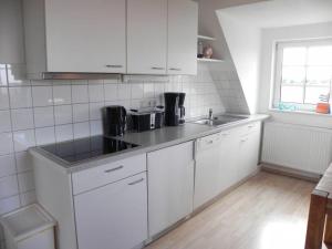 a kitchen with white cabinets and a sink at Haus Nordlicht Ferienwohnung *Auer Lun* in Nebel