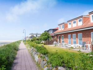 a sidewalk next to a house and the beach at Südspitze 34 Whg. 26 in Wittdün