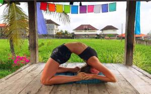 a woman doing a yoga pose on a wooden floor at In Da Lodge in Ubud