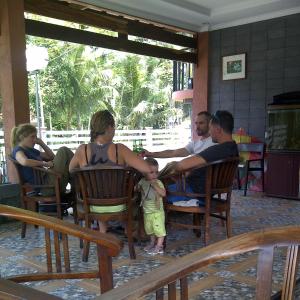 Amazon Bungalow & Cottages في Batukaras: مجموعة من الناس يجلسون على الكراسي مع طفل