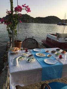 una mesa con comida junto a un cuerpo de agua en Kekova Theimussa en Kaleucagız