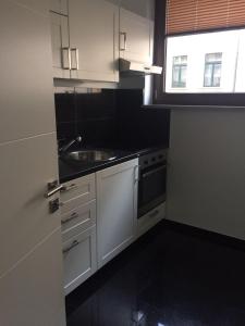 Una cocina con gabinetes blancos y un fregadero y una ventana. en Bambus, en Leipzig 9 fotos más