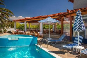 a pool with chairs and umbrellas on a patio at Votsalakia Hotel in Marathokampos