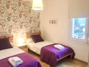 a bedroom with two beds with purple sheets and a window at Apartamento Tossa de Mar in Tossa de Mar