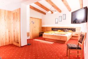 Schlafzimmer mit einem Bett und einem Flachbild-TV in der Unterkunft Gasthof Knappenwirt in Mariahof