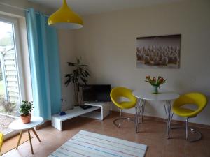 a living room with yellow chairs and a table and a tv at Boddenpieper in Born