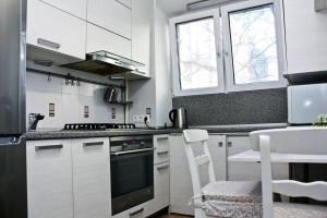 cocina con armarios blancos y fogones en Alliance Apatrments on Sokolova, en Rostov-on-Don