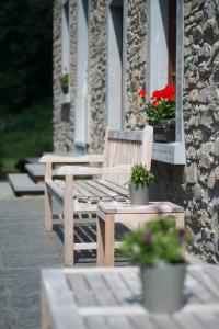 dwie drewniane ławki siedzące na zewnątrz budynku z kwiatami w obiekcie Hotel Le Moulin Simonis w mieście Laforêt