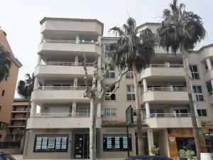 een wit gebouw met palmbomen ervoor bij Albir Sunshine Apartments in Albir