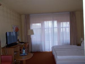 a hotel room with a bed and a television at Berg-Gasthof Honigbrunnen in Löbau