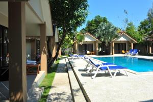 a swimming pool with lounge chairs next to a house at Light Khao Lak Resort in Khao Lak