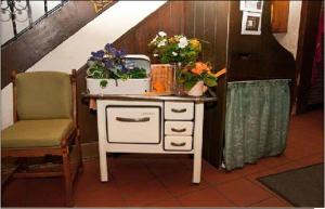 a dresser with flowers on it next to a chair at Hotel Ratskeller Gehrden in Gehrden