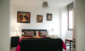 ein Schlafzimmer mit einem schwarzen Bett mit Bildern an der Wand in der Unterkunft Alameda Guest House GF in Espinho