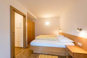 um quarto com uma cama com lençóis brancos e almofadas em Haus Gufler em Silandro