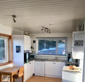 a kitchen with white cabinets and a table and a window at The Stroops in Helmsdale