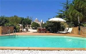 a large swimming pool with an umbrella and chairs at TrulliColarossa in Alberobello